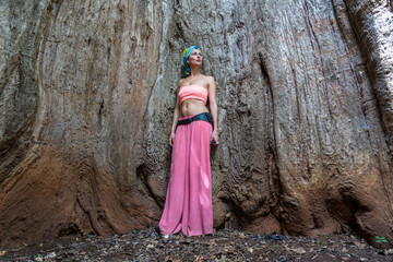 A beautiful girl is standing inside the trunk of an old baobab tree on the island of Zanzibar,...