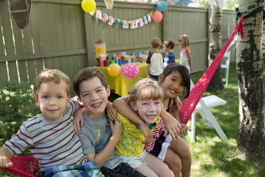 Portrait smiling kids hammock backyard birthday party