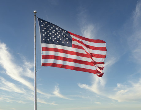 American flag flies high on a windy day with blue skies