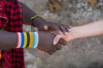 Masai tribal man with a caucasian girl making a handshake in the street on the island of Zanzibar,...
