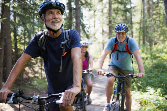 Smiling senior man mountain biking in woods