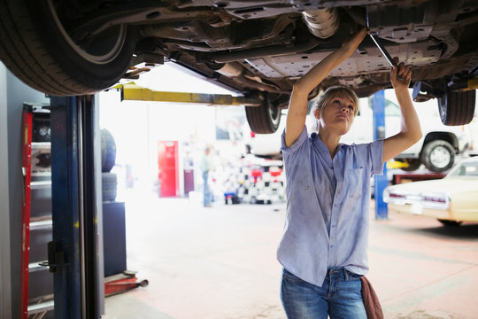 Female mechanic working underneath car auto repair shop
