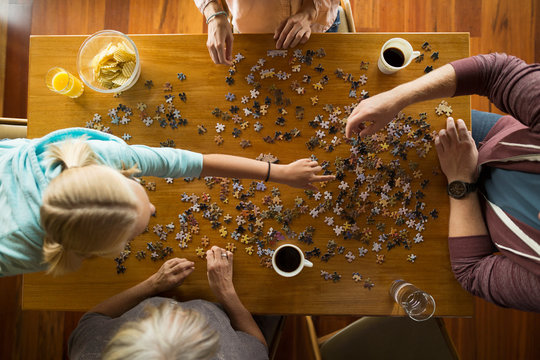 Overhead view family assembling jigsaw puzzle at table