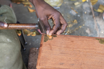 African man hammer a nail into a wooden box on the street on the island of Zanzibar, Tanzania, Africa, close up