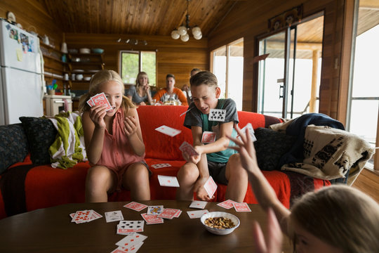 Playful cousins flicking cards in cabin