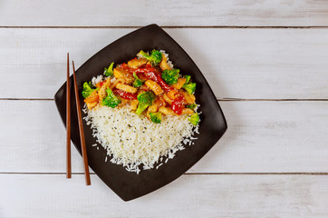 Rice with stir fry chicken and vegetable on black square plate. Chinese cuisine.