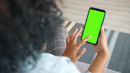 Back view of woman brunette using green screen smartphone touching screen swiping surfing the Internet. Modern technology and entertainment concept. - Powered by Adobe