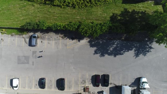 Two People Walking Towards Grey Mini Van And Getting Inside In Parking Lot Drone Aerial
