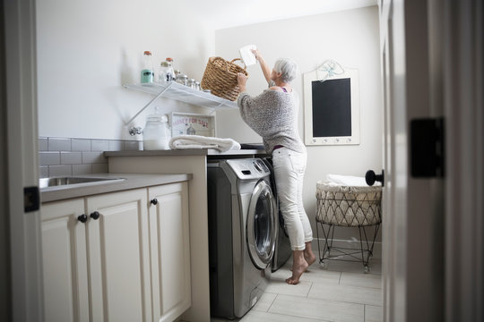 Woman Reaching For Basket In Laundry Room
