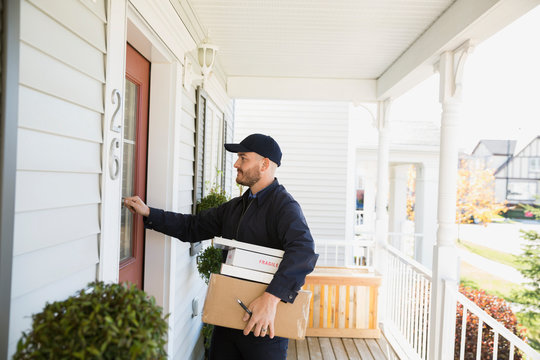 Delivery man with packages knocking at front door