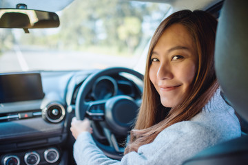 Closeup image of a woman holding steering wheel while driving a car on the road