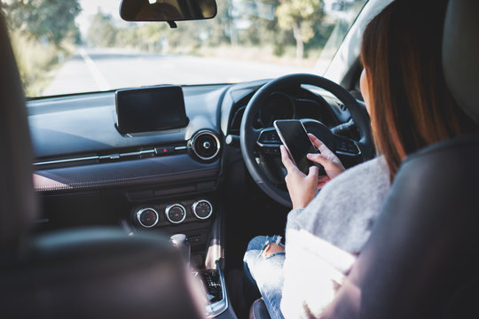 Closeup image of a woman using mobile phone while driving a car