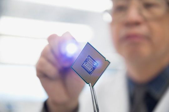 Focused engineer examining microchip with flashlight