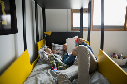 Father and son reading book on bed