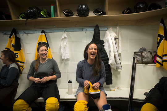 Laughing women ice hockey players dressing locker room