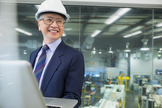 Smiling manager using laptop in factory