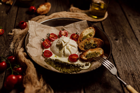 Italian Buratto cheese, delicious cheese, appetizer of cheese, cherry and arugula, cheese dish