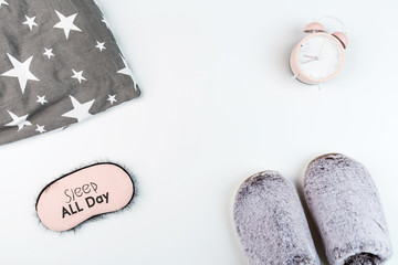 Flat lay with Soft fluffy slippers gray color, pillow, blindfold and pink alarm clock isolated on white background. top view, overhead, mockup, template, copy space. Time for rest