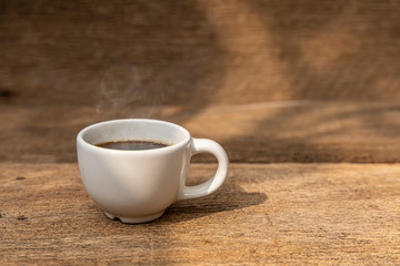 A white cup of coffee on the wooden table background.