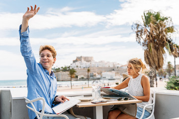guy asking the waiter at an outdoor restaurant during a date with a young girl