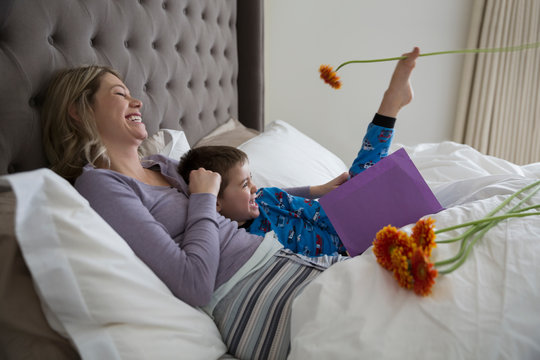 Playful son giving Mother¬å¬çs Day card in bed