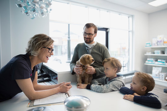 Veterinarian greeting family with dog at reception