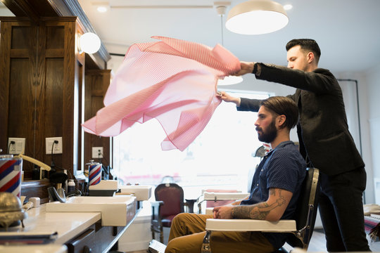 Barber Flipping Smock Over Customer In Barber Shop