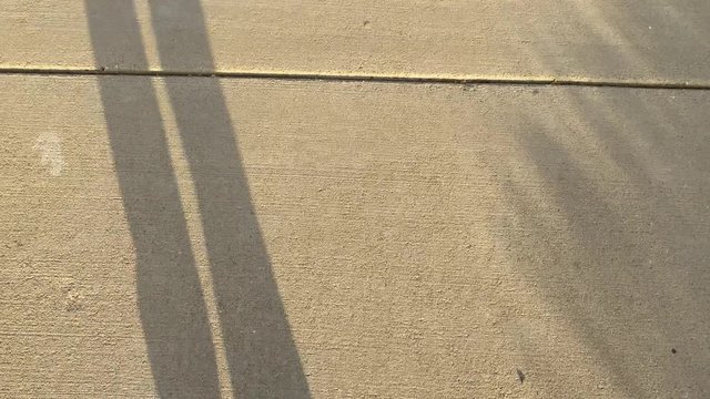 Man is walking along the road. Shadow of the legs against the sunset. Camera is looking down. Abstract Concept of improve, success, effort.