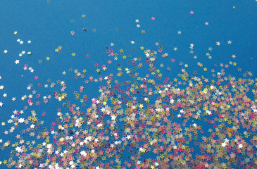Gold stars confetti abstract pattern on a white background. Holiday concept, top view.