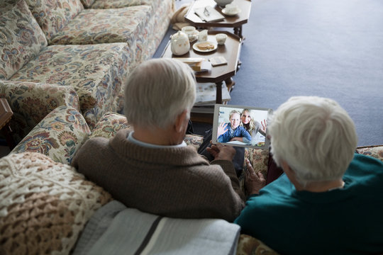 Senior couple video chatting with daughter and grandson on digital tablet