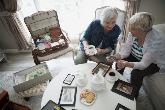Senior women drinking tea and looking at old photographs