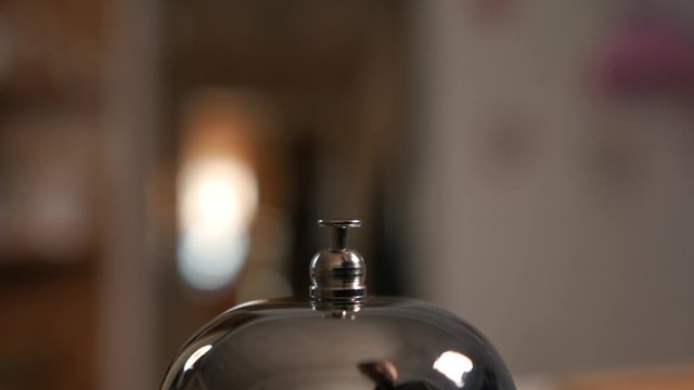 Closeup of a call to the front Desk of the hotel. Men finger presses the bell.