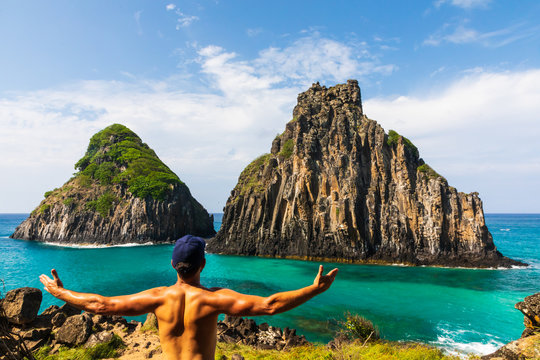 To promote sustainable tourism, solo traveler embrace Morro dos Dois Irm&atilde;os in Fernando de Noronha, Brazil. Solo hiker. Stunning view of volcanic landscape of Two Brothers Mountain.