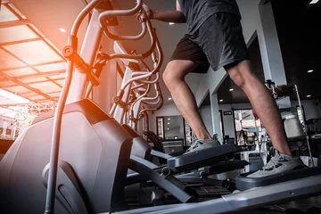 Crédence de cuisine en verre imprimé Fitness Young man working out on an elliptical trainer in gym