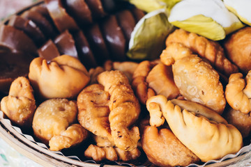 Kakanin AKA Filipino native delicacies in  party size bamboo tray consisting of kutsinta or cuchinta (brown rice cake), puto (steamed rice cakes or buns), and empanada (stuffed bread). Selected focus.