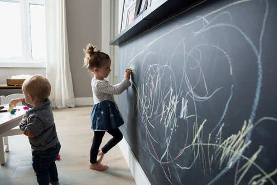 Girl drawing on blackboard wall in playroom
