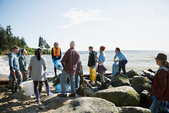 Beach cleanup volunteers on sunny beach rocks