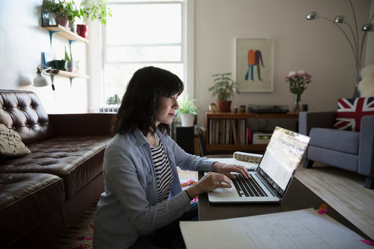 Female architect working at laptop in living room