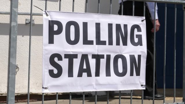 4K: Polling Station Sign - People walking past and going to vote in the election. Politics. Wide Shot