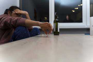 woman is sitting at the table and crying. in front of her is a bottle of wine. engagement ring...