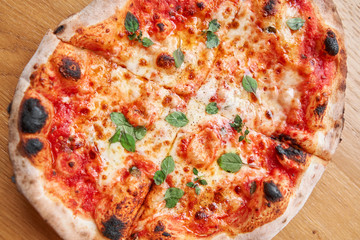 Pizza Margarita. Baked tasty margherita pizza in Traditional wood oven in Neapolitan restaurant, Italy.