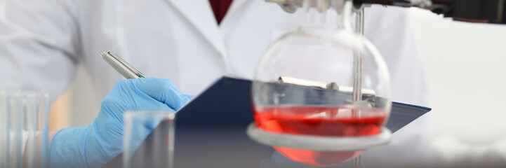 Female chemist in the laboratory of biological analysis portrait doing notes on paper results