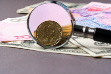 Magnifying glass on ukrainian hryvnia and Us dollars banknotes. Exchange rate concept