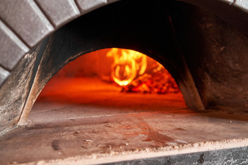 Firewood is burning, the stove is being heated. Red hot coal. Traditional wood oven in Naples restaurant, Italy. Original neapolitan pizza.