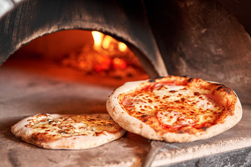 Baked tasty margherita pizza in Traditional wood oven in Naples restaurant, Italy. Original neapolitan pizza. Red hot coal. - obrazy, fototapety, plakaty