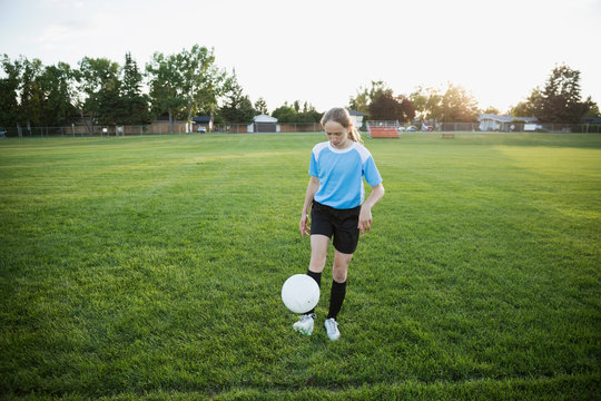 Middle school girl soccer player practicing juggling soccer ball on field