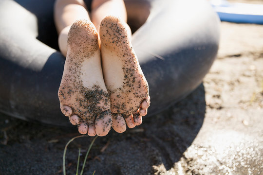 Close up barefoot teenage girl with sand on feet on sunny summer beach