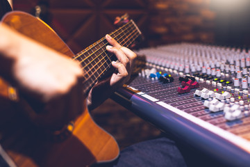 male musician playing acoustic guitar for recording in home studio