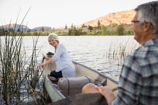 Retired Couple Laughing And Canoeing On Tranquil Lake