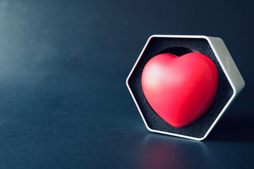 Big red heart in white hexagon gift box with black background, Natural light. Feeling of delivering...